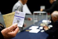 A person shows his election certificate prior casts his vote for the French parliamentary elections at a polling station in Le Touquet, northern France on June 12, 2022. (Photo by Ludovic MARIN / AFP)