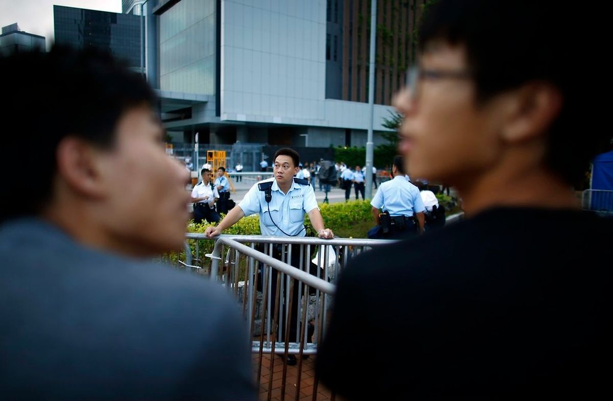 A police officer stands next to metal fences as protesters block the entrance of Hong Kong Chief Executive Leung Chun-ying's offices, next to the government headquarters building in Hong Kong, October 2, 2014. Hong Kong's leader is willing to let pro-democracy demonstrations blocking large areas of the city go on for weeks if necessary, a source close to him said, while defiant protesters vowed they would not budge. REUTERS/Carlos Barria (CHINA - Tags: CIVIL UNREST POLITICS)