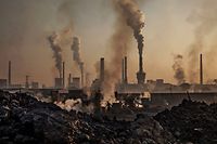 INNER MONGOLIA, CHINA - NOVEMBER 04: Smoke billows from a large steel plant as a Chinese labourer works at an unauthorized steel factory, foreground, on November 4, 2016 in Inner Mongolia, China. To meet China's targets to slash emissions of carbon dioxide, authorities are pushing to shut down privately owned steel, coal, and other high-polluting factories scattered across rural areas. In many cases, factory owners say they pay informal 'fines' to local inspectors and then re-open. The enforcement comes as the future of U.S. support for the 2015 Paris Agreement is in question, leaving China poised as an unlikely leader in the international effort against climate change. U.S. president-elect Donald Trump has sent mixed signals about whether he will withdraw the U.S. from commitments to curb greenhouse gases that, according to scientists, are causing the earth's temperature to rise. Trump once declared that the concept of global warming was "created" by China in order to hurt U.S. manufacturing. China's leadership has stated that any change in U.S. climate policy will not affect its commitment to implement the climate action plan. While the world's biggest polluter, China is also a global leader in establishing renewable energy sources such as wind and solar power. (Photo by Kevin Frayer/Getty Images)