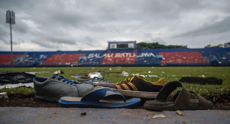 TOPSHOT - Discarded shoes sit by the pitch at Kanjuruhan stadium days after a deadly stampede following a football match in Malang, East Java on October 3, 2022. - Anger against police mounted in Indonesia on October 3 after at least 125 people were killed in one of the deadliest disasters in the history of football, when officers fired tear gas in a packed stadium, triggering a stampede. (Photo by Juni Kriswanto / AFP)
