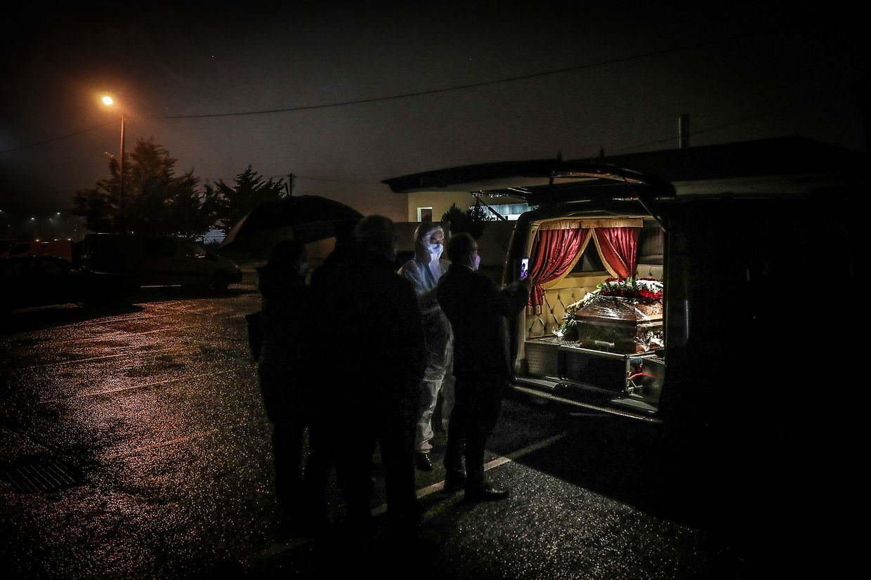 Funcionários de uma agência funerária e familiares de uma vítima de covid-19, despedem-se no parque de estacionamento do Crematório de Rio de Mouro, em Sintra, a 29 de janeiro de 2021.