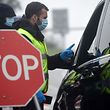 Checkpoint personnel and Portuguese National Republican Guards talk to a driver at a checkpoint in the Portuguese-Spanish border crossing between Valenca and Tui on January 31, 2021. - Portugal imposed controls on its border with Spain in an attempt to contain the spread of the coronavirus pandemic. Travel abroad will be limited for two weeks starting today. (Photo by MIGUEL RIOPA / AFP)