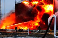 Bombeiros tentam apagar um incêndio após a queda de mísseis russos numa instalação de armazenamento de combustível na cidade ucraniana ocidental de Lviv