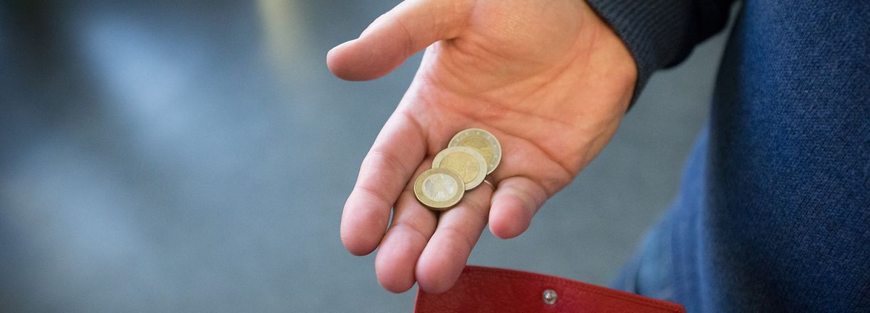 ARCHIV - 31.01.2017, Nordrhein-Westfalen, Paderborn: ILLUSTRATION - Münzen werden über ein rotes Portemonnaie gehalten. (zur dpa-Umfrage "Umfrage: Gut ein Viertel der Bürger kann am Monatsende kaum sparen" am 09.11.2019) Foto: Friso Gentsch/dpa +++ dpa-Bildfunk +++