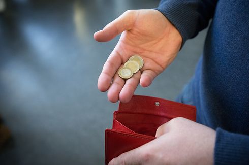 ARCHIV - 31.01.2017, Nordrhein-Westfalen, Paderborn: ILLUSTRATION - Münzen werden über ein rotes Portemonnaie gehalten. (zur dpa-Umfrage "Umfrage: Gut ein Viertel der Bürger kann am Monatsende kaum sparen" am 09.11.2019) Foto: Friso Gentsch/dpa +++ dpa-Bildfunk +++