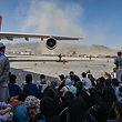 Afghan people sit as they wait to leave Kabul airport 