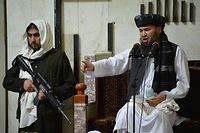 An armed Taliban fighter (L) stands next to Mullah, a religious leader, speaking during Friday prayers at the Pul-e Khishti Mosque in Kabul on September 3, 2021. (Photo by HOSHANG HASHIMI / AFP)