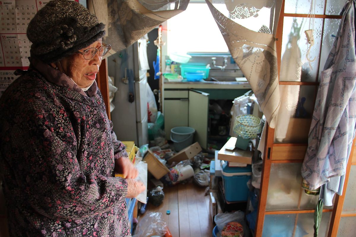 Eine ältere Japanerin steht fassungslos vor ihrer verwüsteten Küche.