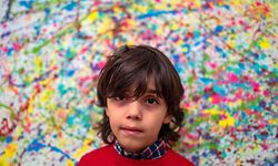 7-year-old German artist Mikail Akar poses in front of a limited print edition of his "Champi" painting, prior to the opening of his "Manus 11" exhibition in Berlin on December 13, 2019. - Manus 11 refers to a work he painted with German goalkeeper Manuel Neuer. (Photo by John MACDOUGALL / AFP)