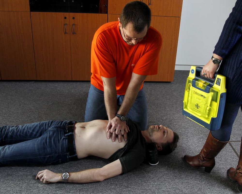 4) Herzmassage: Es sollte sofort mit der Herzdruckmassage begonnen werden. Dazu das Notfallopfer rücklings und auf eine harte Oberfläche legen. Seitlich daneben knien und den Ballen einer Hand auf die Mitte der Brust legen. Den Ballen der anderen Hand auf die erste Hand legen und die Finger ineinander verschränken. Das Brustbein ca. fünf bis sechs Zentimeter nach unten drücken. Nach jeder Herzdruckmassage den Brustkorb vollständig entlasten. Die Massage muss 120 Mal in der Minute erfolgen. Mit der Herzdruckmassage muss fortgefahren werden, bis der Patient wach ist oder der Rettungsdienst eintrifft. Zeitgleich sollte, im besten Fall, eine zweite anwesende Person einen Defibrillator besorgen.