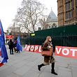 A pedestrian walks pas a placard reading "People's Vote" as Brexit activits demonstrate outside of the Houses of Parliament in central London on January 21, 2019, whilst Britain's Prime Minister Theresa May makes a statement to the House of Commons on changes to her Brexit withdrawal agreement. - British Prime Minister Theresa May unveils her Brexit "Plan B" to parliament on Monday after MPs shredded her EU divorce deal, deepening the political gridlock 10 weeks from departure day. (Photo by Tolga AKMEN / AFP)
