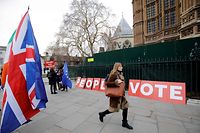 A pedestrian walks pas a placard reading "People's Vote" as Brexit activits demonstrate outside of the Houses of Parliament in central London on January 21, 2019, whilst Britain's Prime Minister Theresa May makes a statement to the House of Commons on changes to her Brexit withdrawal agreement. - British Prime Minister Theresa May unveils her Brexit "Plan B" to parliament on Monday after MPs shredded her EU divorce deal, deepening the political gridlock 10 weeks from departure day. (Photo by Tolga AKMEN / AFP)