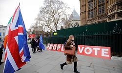 A pedestrian walks pas a placard reading "People's Vote" as Brexit activits demonstrate outside of the Houses of Parliament in central London on January 21, 2019, whilst Britain's Prime Minister Theresa May makes a statement to the House of Commons on changes to her Brexit withdrawal agreement. - British Prime Minister Theresa May unveils her Brexit "Plan B" to parliament on Monday after MPs shredded her EU divorce deal, deepening the political gridlock 10 weeks from departure day. (Photo by Tolga AKMEN / AFP)