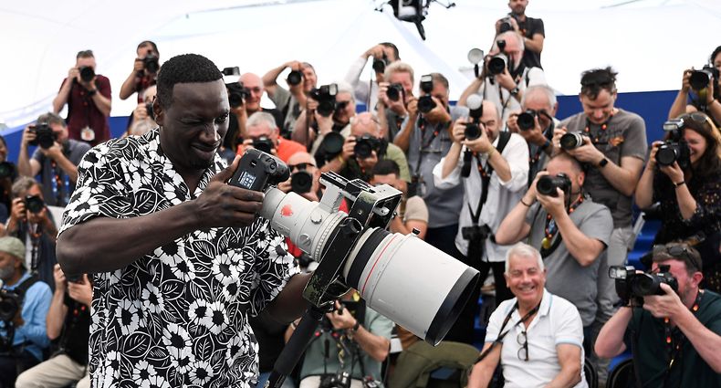 O ator e comediante francês Omar Sy posa com uma máquina fotográfica durante a 75ª edição do Festival de Cinema de Cannes, a 19 de Maio de 2022. 