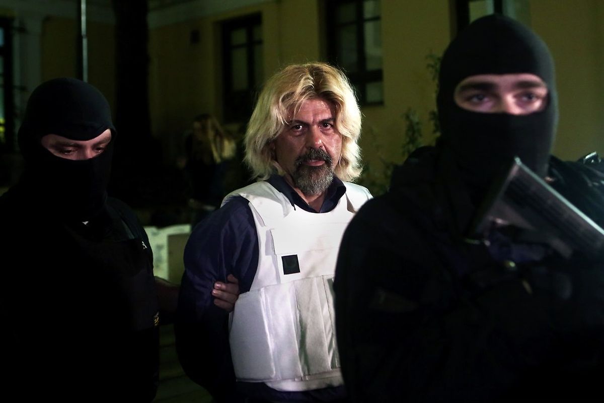 Greek fugitive Christodoulos Xiros is escorted by anti-terrorism police officers as he leaves the prosecutor's office after been recaptured on January 4, 2015, in Athens. Xiros was taken into custody in the southern suburb of Anavyssos just shy of a year following his January 7, 2014 disappearance while on prison leave. He had serving multiple life sentences for deadly attacks he participated in as a hitman for the November 17 group and had been on a nine-day New Year's break when he disappeared. AFP PHOTO / ANGELOS TZORTZINIS