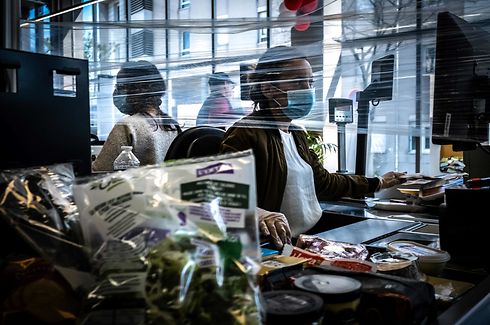 A cashier works wearing a face mask in a supermarket on April 15, 2020, in Givors, near Lyon, on the 30th day of a strict lockdown in France aimed at curbing the spread of the COVID-19 infection caused by the novel coronavirus. (Photo by JEAN-PHILIPPE KSIAZEK / AFP)