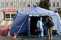 People arrive at the a pre-triage medical tent in front of the Cremona hospital, in Cremona, northern Italy, on March 4, 2020. - Italy will recommend people stop kissing in public, avoid shaking hands and keep a safe distance from each other to limit the spread of the novel coronavirus. Other measures to be approved by the government, which has borne the brunt of the COVID-19 disease, includes a plan to play all football matches behind closed doors. (Photo by Miguel MEDINA / AFP)