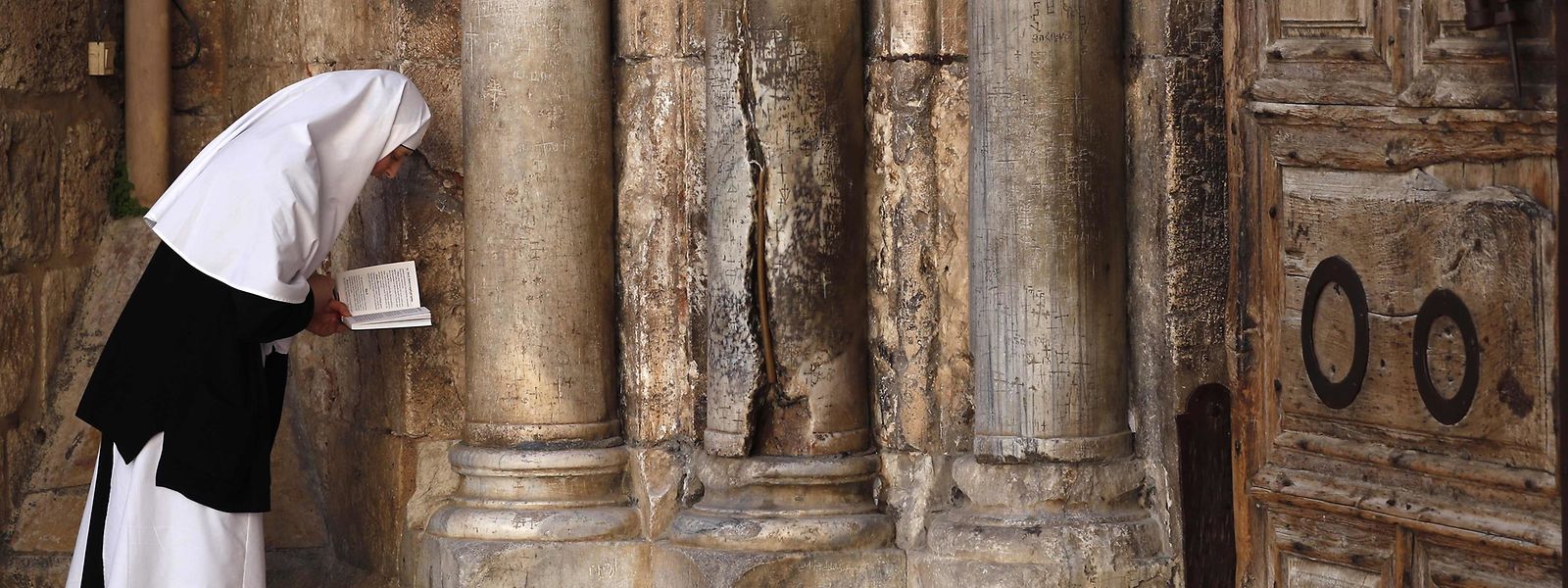 Vor der verschlossenen Tür der Jerusalemer Grabeskirche betet eine Nonne.