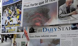 A woman passes in front of a newspaper stall, selling Lebanese newspapers featuring on their front pages images of the fire that ravaged the Parisian Notre Dame cathedral, in the capital Beirut on April 16, 2019. - Paris was struck in its very heart as flames devoured the roof of Notre-Dame, the medieval cathedral made famous by Victor Hugo, its two massive towers flanked with gargoyles instantly recognisable even by people who have never visited the city. (Photo by ANWAR AMRO / AFP)