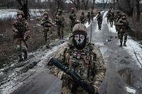 TOPSHOT - Ukrainian servicemen walk on the road toward their base near the frontline in the Donetsk region on February 4, 2023, amid the Russian invasion of Ukraine. (Photo by YASUYOSHI CHIBA / AFP)