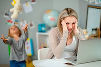 Young daughter plays and works beside her mother in their home office.