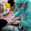 A medical staff member collects blood samples on a resident to detect the COVID-19 (novel coronavirus) in the sports hall of the small town of Robbio, northern Italy, on April 4, 2020, as part of an initiative of the mayor, as Italy's three-week lockdown to stop the spread of COVID-19 has been extended through at least mid-April. (Photo by Miguel MEDINA / AFP)