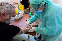 A medical staff member collects blood samples on a resident to detect the COVID-19 (novel coronavirus) in the sports hall of the small town of Robbio, northern Italy, on April 4, 2020, as part of an initiative of the mayor, as Italy's three-week lockdown to stop the spread of COVID-19 has been extended through at least mid-April. (Photo by Miguel MEDINA / AFP)