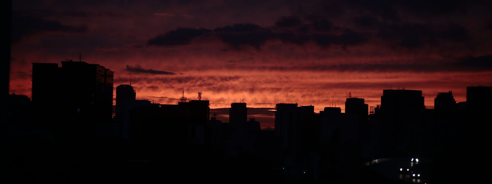 Venezuela, Caracas: Die Sonne geht hinter dunklen Häusern unter. Erneut ist Venezuela von einem massiven Stromausfall betroffen. 