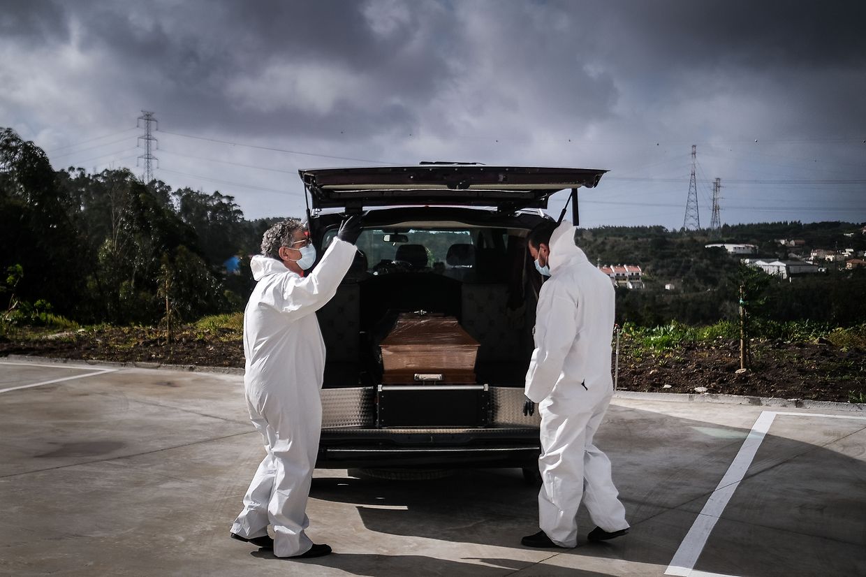 Funcionários de uma agência funerária observam um caixão de uma mulher que morreu vítima de covid-19, junto ao Complexo Funerário Casal de Cambra, em Sintra, a 30 de janeiro de 2021. 
