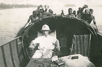 Ein luxemburgischer Kolonialverwalter in einem Boot, das von kongolesischen Paddlern gesteuert wird. 1930er Jahre.
