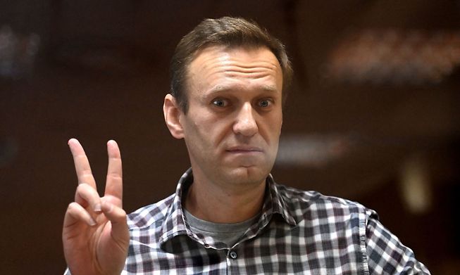 Russian opposition leader Alexei Navalny gestures a V sign from inside a glass cell during a court hearing on February 20, 2021 