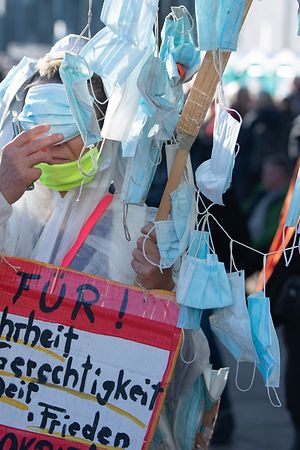 ARCHIV - 07.11.2020, Sachsen, Leipzig: Eine Teilnehmerin der Demonstration der Stuttgarter Initiative "Querdenken" steht mit einem selbst gebastelten "Baum", an dem Nase-Mundschutzmasken hängen, auf dem Augustusplatz (zu dpa «Nach der «Querdenken»-Demonstration vom vergangenen Wochenende in Leipzig»). Foto: Sebastian Kahnert/dpa-Zentralbild/dpa +++ dpa-Bildfunk +++