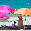 05.08.2022, Spanien, Palma: Eine Frau sitzt neben ihrem Kind unter einem Sonnenschirm an einem warmen Sommertag am Strand. Foto: Clara Margais/dpa +++ dpa-Bildfunk +++