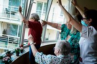 TOPSHOT - Staff members and residents salute their families at the elderly residence Christalain on April 17, 2020, in Brussels, during a strict lockdown in the country to fight against the novel coronavirus. (Photo by kenzo tribouillard / AFP)
