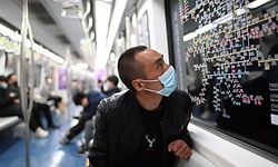 A man wearing a face mask, amid concerns of the COVID-19 coronavirus, looks at a subway map on a train in Beijing on April 3, 2020. (Photo by WANG ZHAO / AFP)
