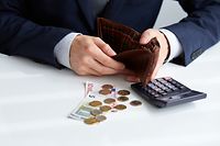 Businessman with empty wallet and a few coins on the table