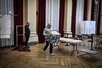 A city hall employee carries a ballot box in the polling place of the 10th Paris district city hall in Paris on April 8, 2022. - French voters head to the polls on April 10 and 24 for a two-round presidential election. (Photo by STEPHANE DE SAKUTIN / AFP)
