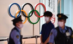 The Olympic rings are seen past policemen (L and R) at the arrival hall of the Tokyo International Airport in Tokyo on July 8, 2021, as International Olympic Committee President Thomas Bach landed in Japan for a visit. (Photo by Kazuhiro NOGI / AFP)