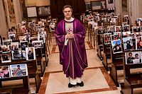 TOPSHOT - Don Giuseppe Corbari, parson of the Church of Robbiano, poses between selfie photographs sent in by his congregation members and  glued to empty pews, before celebrating Sunday mass in Giussano on March 22, 2020. - Italian Prime Minister Giuseppe Conte on March 21 ordered all non-essential companies and factories to close nationwide to stem a coronavirus pandemic that has killed 4,825 people in the country in a month. "The decision taken by the government is to close down all productive activity throughout the territory that is not strictly necessary, crucial, indispensable, to guarantee us essential goods and services," Conte said in a late-night TV address (Photo by Piero CRUCIATTI / AFP)