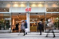 Shoppers walk past a fashion store of H&M (H & M Hennes & Mauritz AB) in central Stockholm on April 2, 2020. - Swedish retailer H&M said that the company have started dialogue with tens of thousands of staff about cutting working hours due to the coronavirus (Covid-19) pandemic effect on the market. (Photo by Fredrik SANDBERG / various sources / AFP) / Sweden OUT