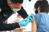 (FILES) In this file photo taken on August 23, 2021 Brandon Rivera, a Los Angeles County emergency medical technician, gives a second does of Pfizer-BioNTech Covid-19 vaccine to Aaron Delgado, 16, at a pop up vaccine clinic in the Arleta neighborhood of Los Angeles, California. - The United States on October 29, 2021 authorized the Pfizer Covid vaccine for children aged five-to-11 after a committee of experts found its benefits outweighed risks. (Photo by Robyn Beck / AFP)