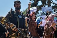 TOPSHOT - Afghan women shout slogans next to a Taliban fighter during an anti-Pakistan demonstration near the Pakistan embassy in Kabul on September 7, 2021. - The Taliban on September 7, 2021 fired shots into the air to disperse crowds who had gathered for an anti-Pakistan rally in the capital, the latest protest since the hardline Islamist movement swept to power last month. (Photo by Hoshang Hashimi / AFP)