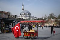 A street vendor sells Turish national flags and corns in Istanbul's Eminonu district on April 27, 2021, two days ahead of a new full lockdown aiming at fighting a surging third wave of coronavirus infections. - Turkey will enter "a full closure", from April 29 to May 17, that requires people to stay indoors without a valid reason and sees all non-essential businesses closed.The nation of 84 million has seen daily Covid-19 death tolls rise to around 350 -- higher than during two previous spikes last year. (Photo by Ozan KOSE / AFP)