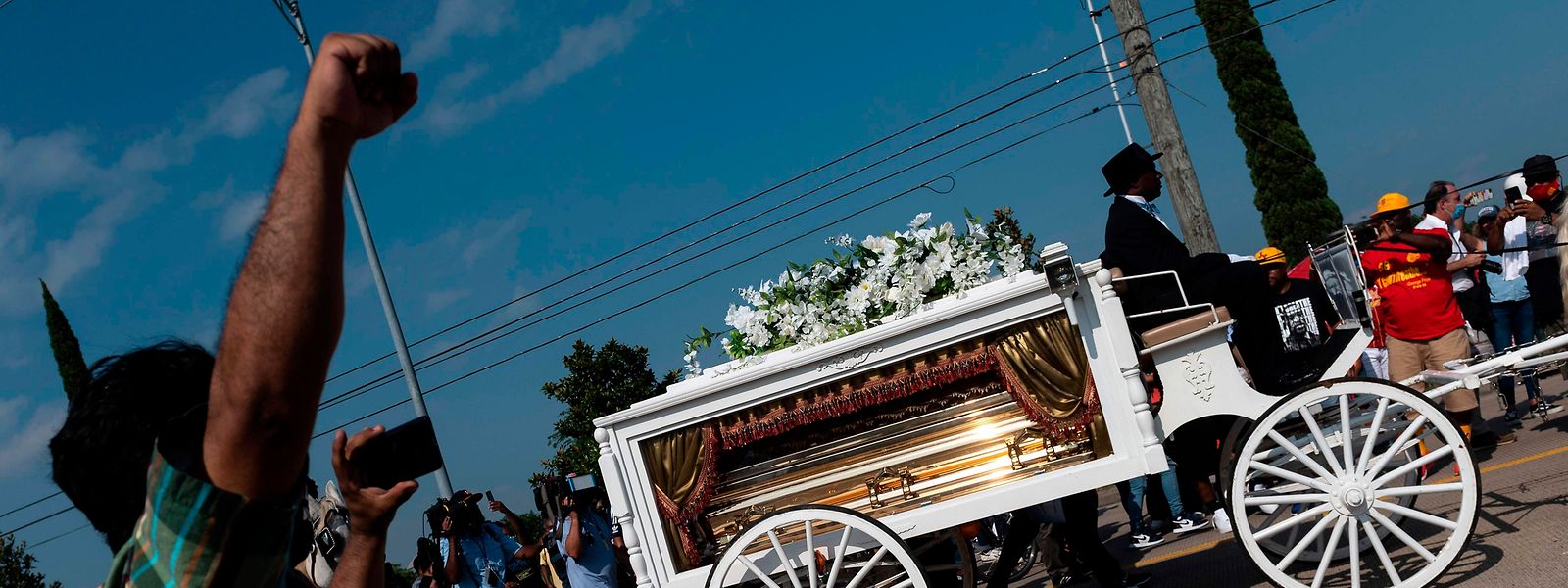 Ein Mann hebt die Faust, während der Sarg von George Floyd von einer weißen Pferdekutsche zu seiner letzten Ruhestätte auf dem Friedhof „Houston Memorial Gardens“ in Pearland gebracht wird.