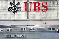 A sign and logo of Credit Suisse bank is seen beneath a sign of Swiss giant banking UBS in Zurich on March 20, 2023. - Shares in European banks sank on March 20, 2022 despite a buyout of Credit Suisse by Swiss lender UBS aimed at preventing a global banking crisis. (Photo by Fabrice COFFRINI / AFP)