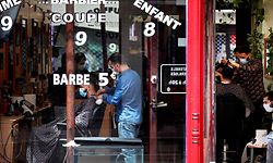 Hairdressers cut hair of clients in Paris on May 11, 2020 on the first day of France's easing of lockdown measures in place for 55 days to curb the spread of the COVID-19 pandemic, caused by the novel coronavirus. (Photo by THOMAS COEX / AFP)