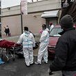 People in Hazmat suits transport a deceased body on a stretcher outside a funeral home in Brooklyn on April 30, 2020 in New York City. - Dozens of bodies have been discovered in unrefrigerated overflow trucks outside the Andrew T. Cleckley Funeral Home, following a complaint of a foul odor. (Photo by Johannes EISELE / AFP)