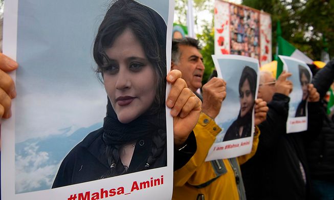 Participants hold up pictures of Mahsa Amini at a protest outside the Iranian Embassy in Berlin on Tuesday 