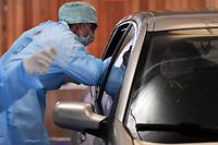 A medical staff takes samples to a driver at a "drive-through" testing facility for the novel coronavirus at the "Hopital de la Citadelle" hospital in Liege, on it's opening day on March 10, 2020. (Photo by ERIC LALMAND / BELGA / AFP) / Belgium OUT