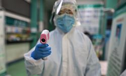 TOPSHOT - A medical worker prepares to check the temperature of an AFP photojournalist before a COVID-19 coronavirus test in Wuhan in China's central Hubei province on April 16, 2020. - China has largely brought the coronavirus under control within its borders since the outbreak first emerged in the city of Wuhan late last year. (Photo by Hector RETAMAL / AFP)
